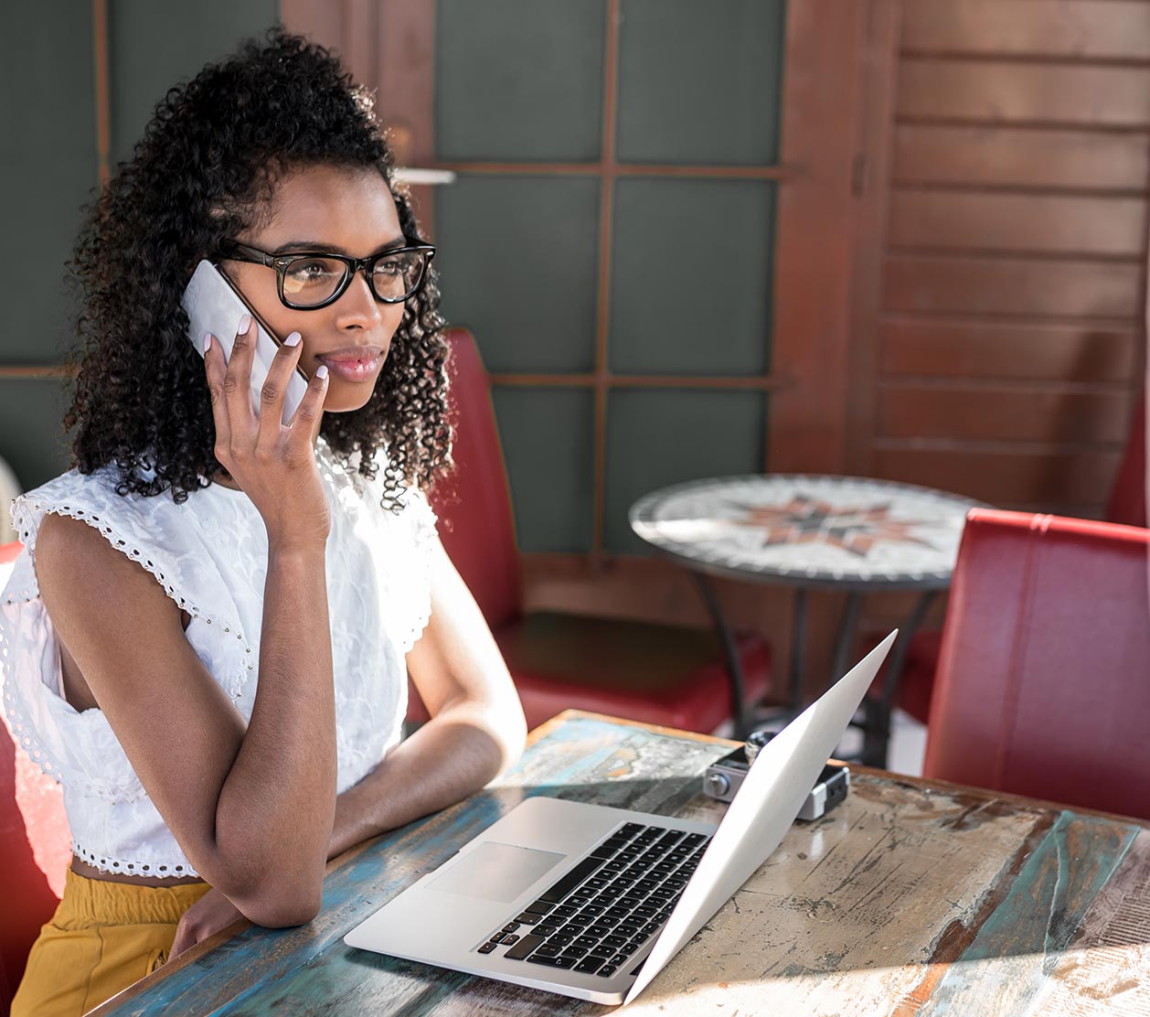 Woman-Talking-on-Phone-at-Table-wih-Laptop